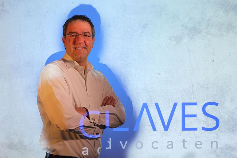 Ralph van den Hoek, staand voor de wand met het geprojecteerde woordmerk van Claves Advocaten.