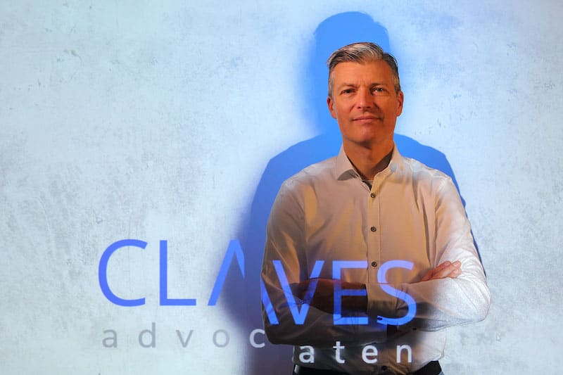 Menno de Jongh, staand voor de wand met het geprojecteerde woordmerk van Claves Advocaten.