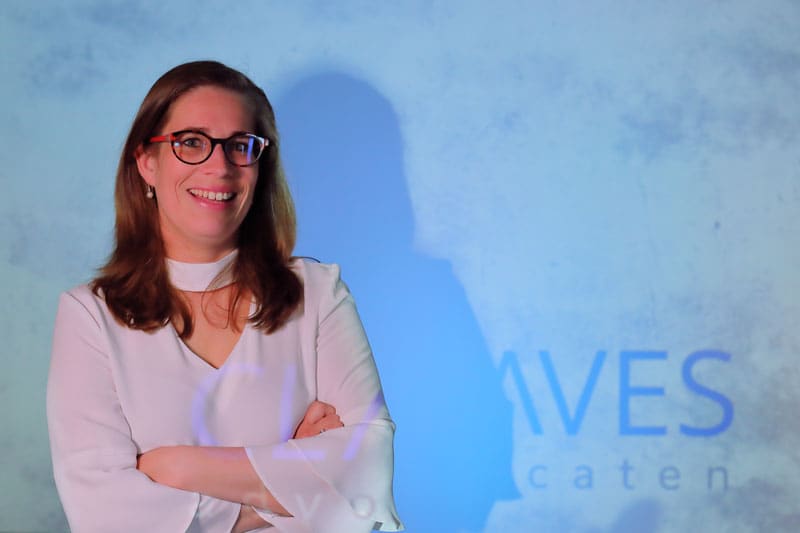 Mandy Priester-Karel, staand voor de wand met het geprojecteerde woordmerk van Claves Advocaten.