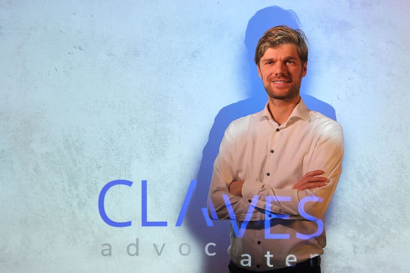 Frank van Steenbergen, staand voor de wand met het geprojecteerde woordmerk van Claves Advocaten.