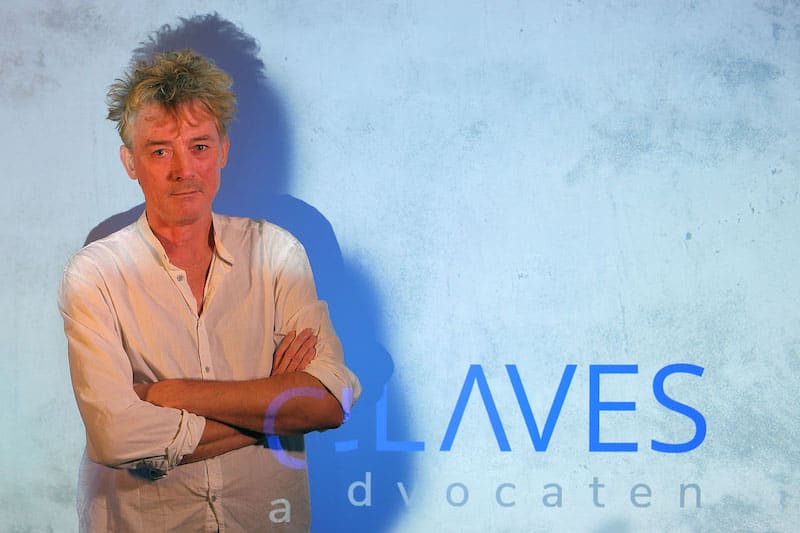 Alex Stipdonk, staand voor de wand met het geprojecteerde woordmerk van Claves Advocaten.