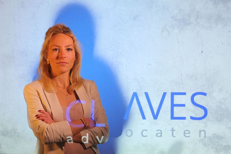 Nina van Amsterdam, staand voor de wand met het geprojecteerde woordmerk van Claves Advocaten.